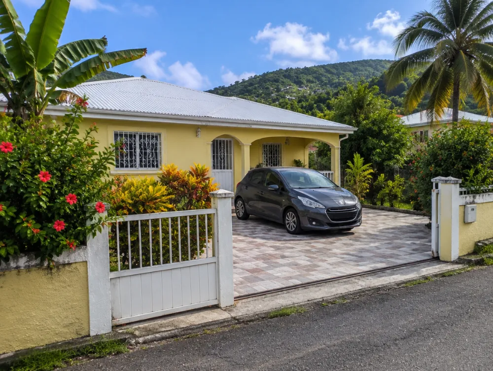 Une voiture garée devant une maison créole jaune, en Martinique